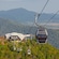 Cable cars traveling above a lush rainforest canopy toward a mountain station